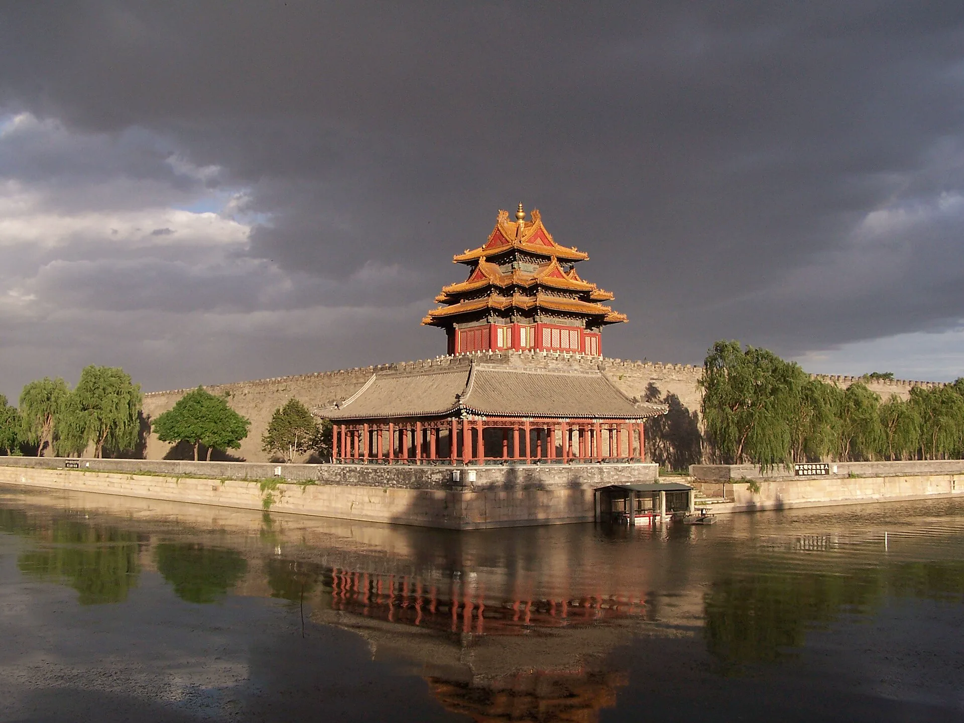 Forbidden City corner tower and moat beneath dramatic evening clouds