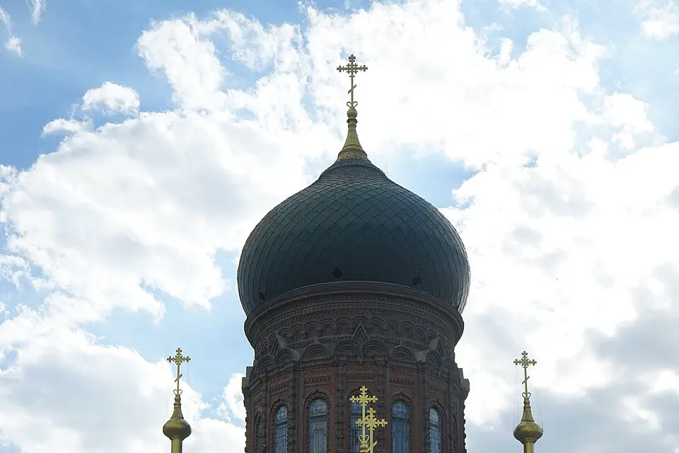 Onion domes and crosses of Saint Sophia Cathedral beneath bright clouds in Harbin