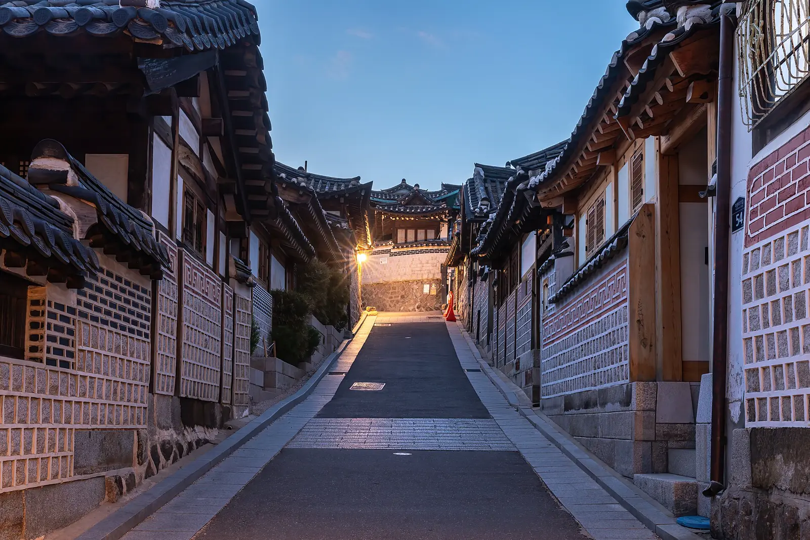 Traditional hanok homes lining a steep Bukchon lane at blue hour