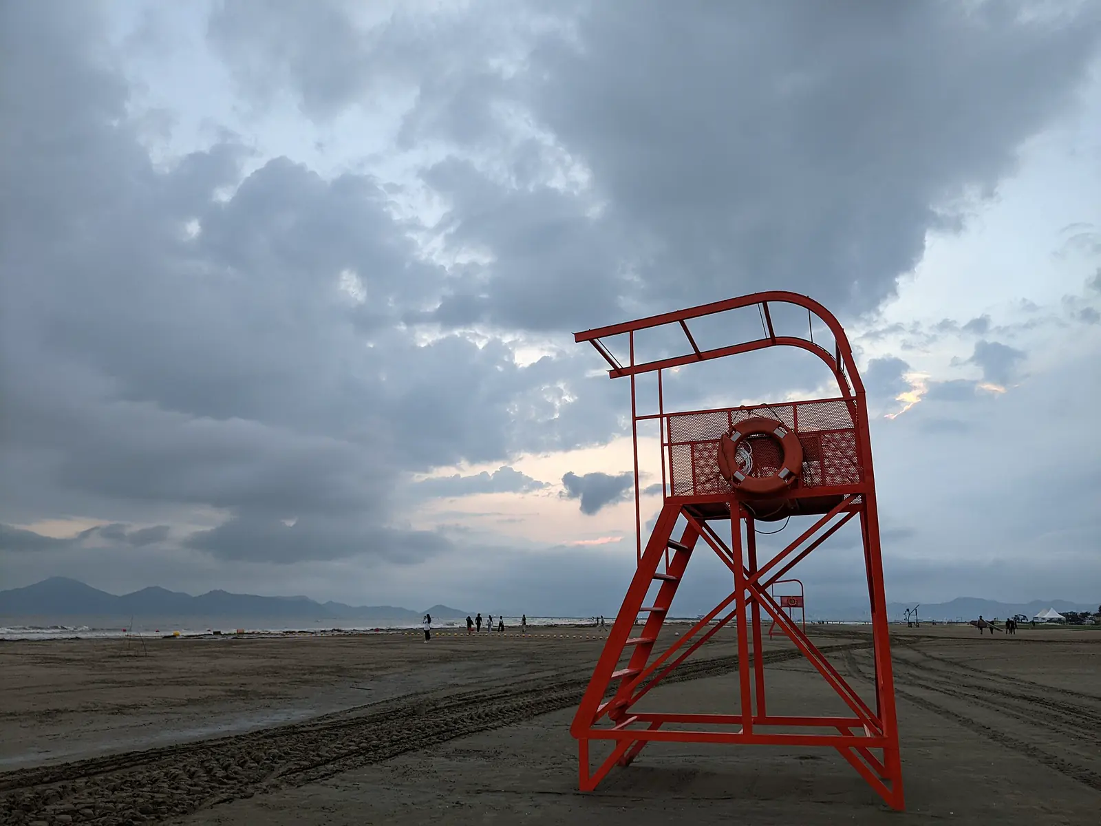 Red lifeguard chair beneath dramatic clouds on Dadaepo Beach