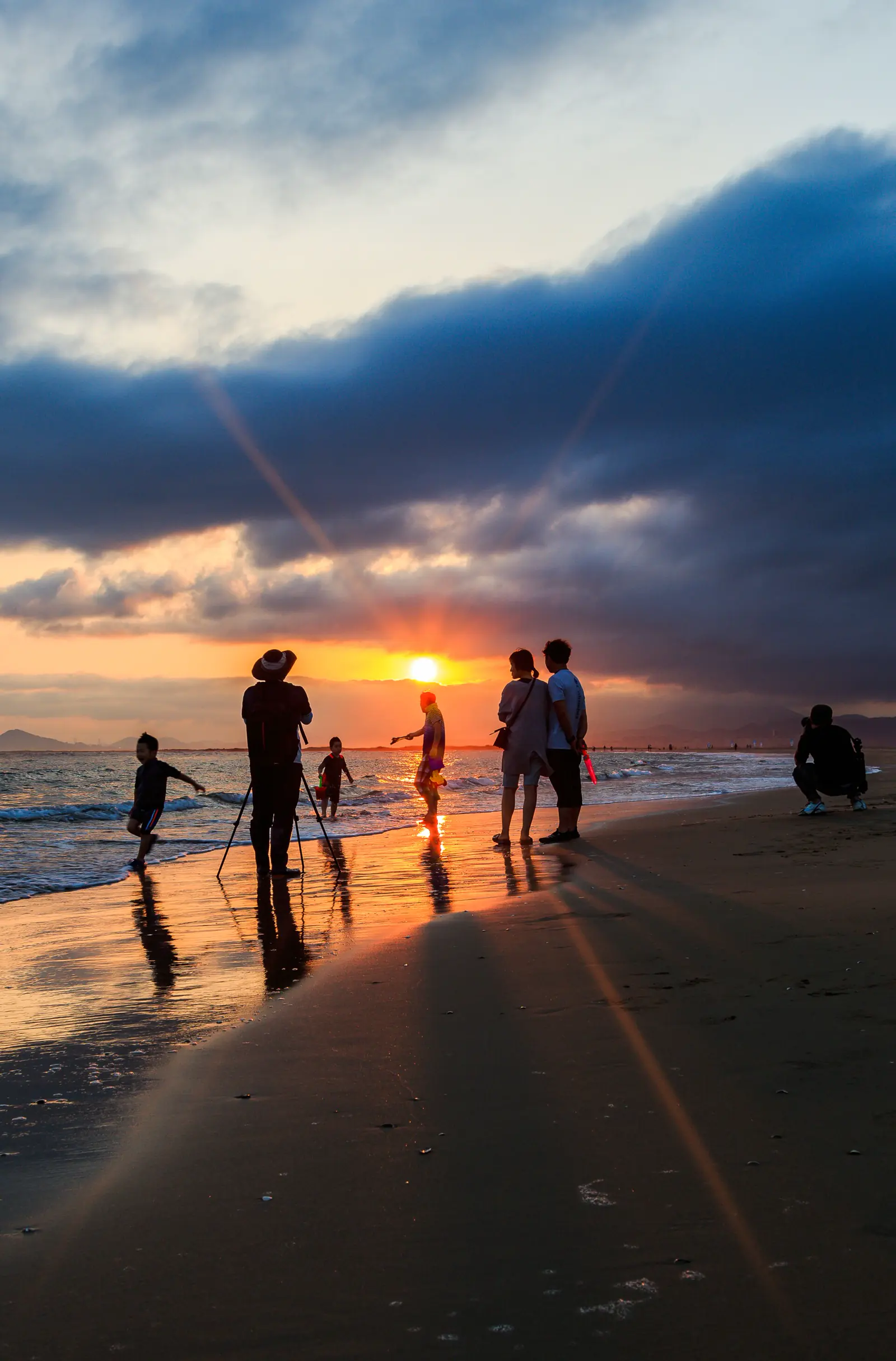 Visitors silhouetted in the shallow light of Dadaepo Beach at sunset
