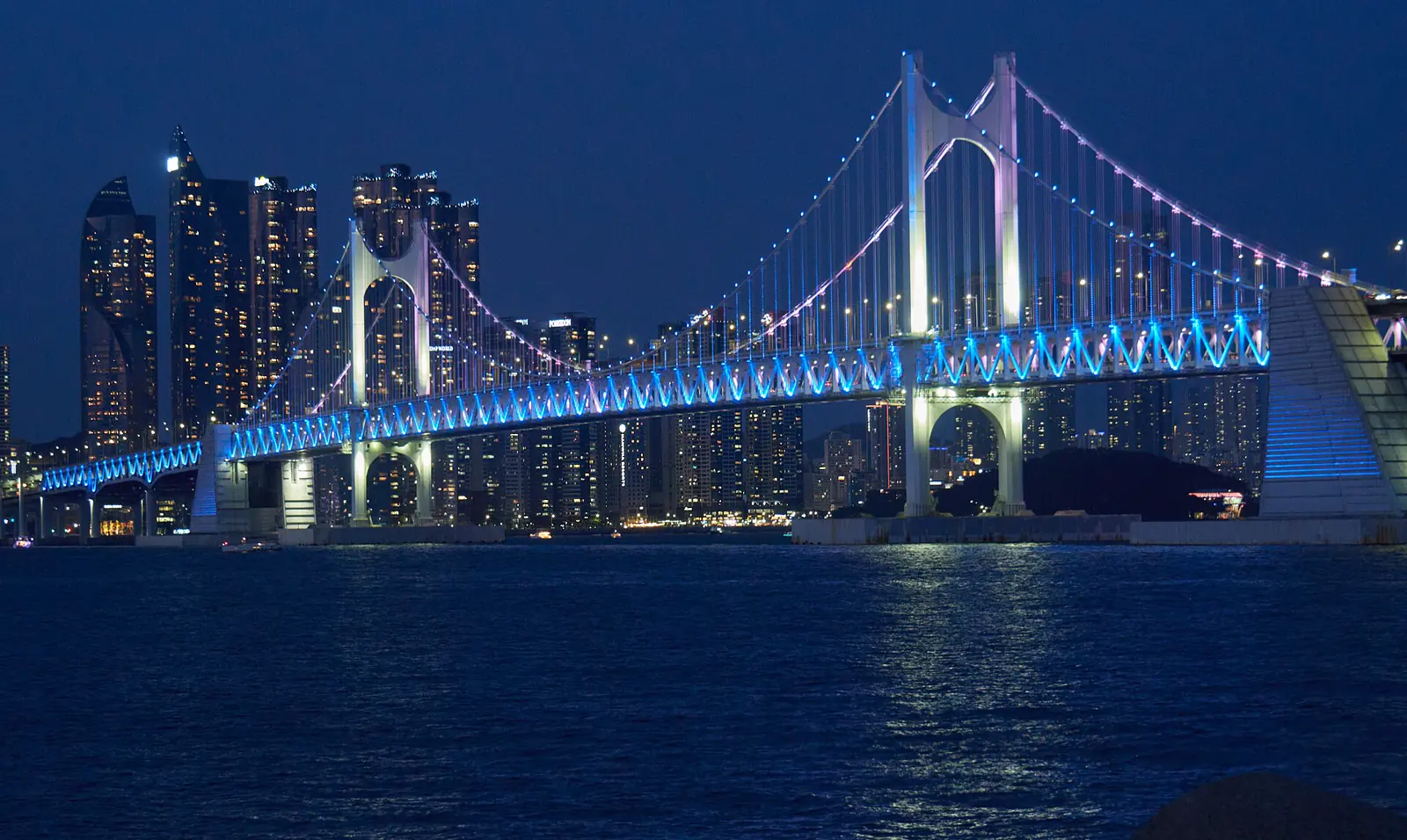 Gwangan Bridge glowing blue over Gwangalli Beach at night