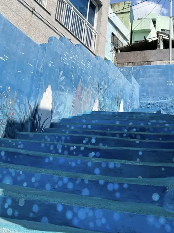 Blue stairway descending through Huinnyeoul Culture Village toward the sea