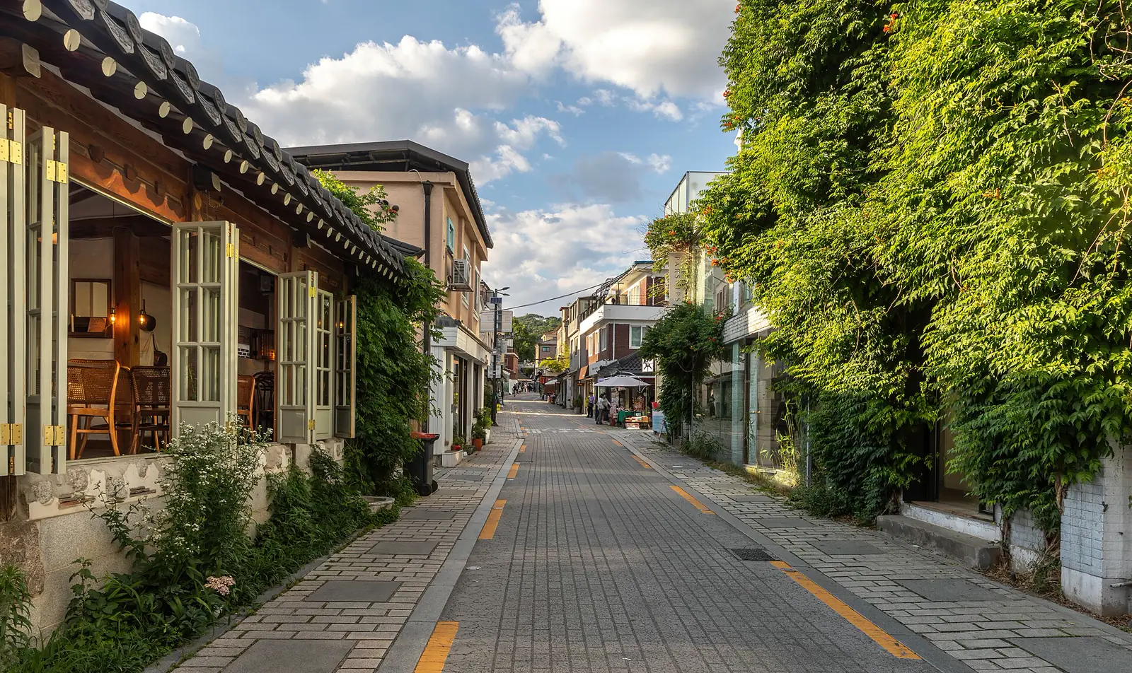 Green vines and small storefronts along a traditional Seoul alley