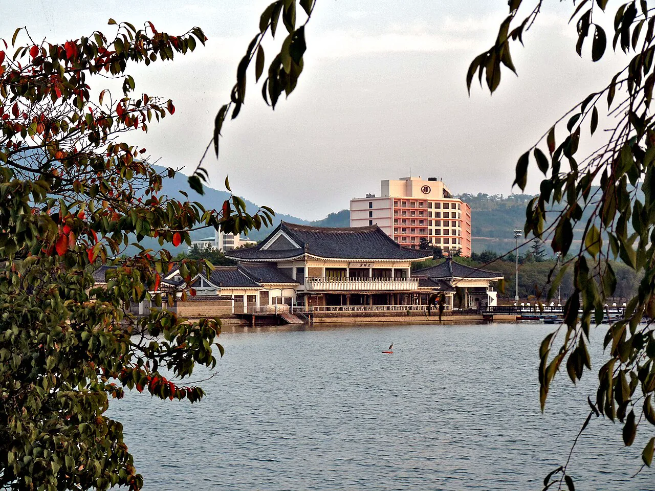 Bomun Lake framed by autumn leaves with lakeside buildings beyond