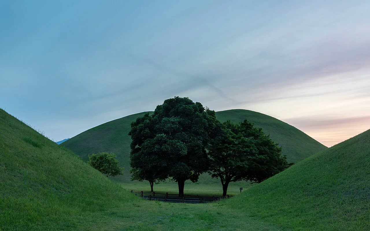 Trees framed by green royal burial mounds in Daereungwon