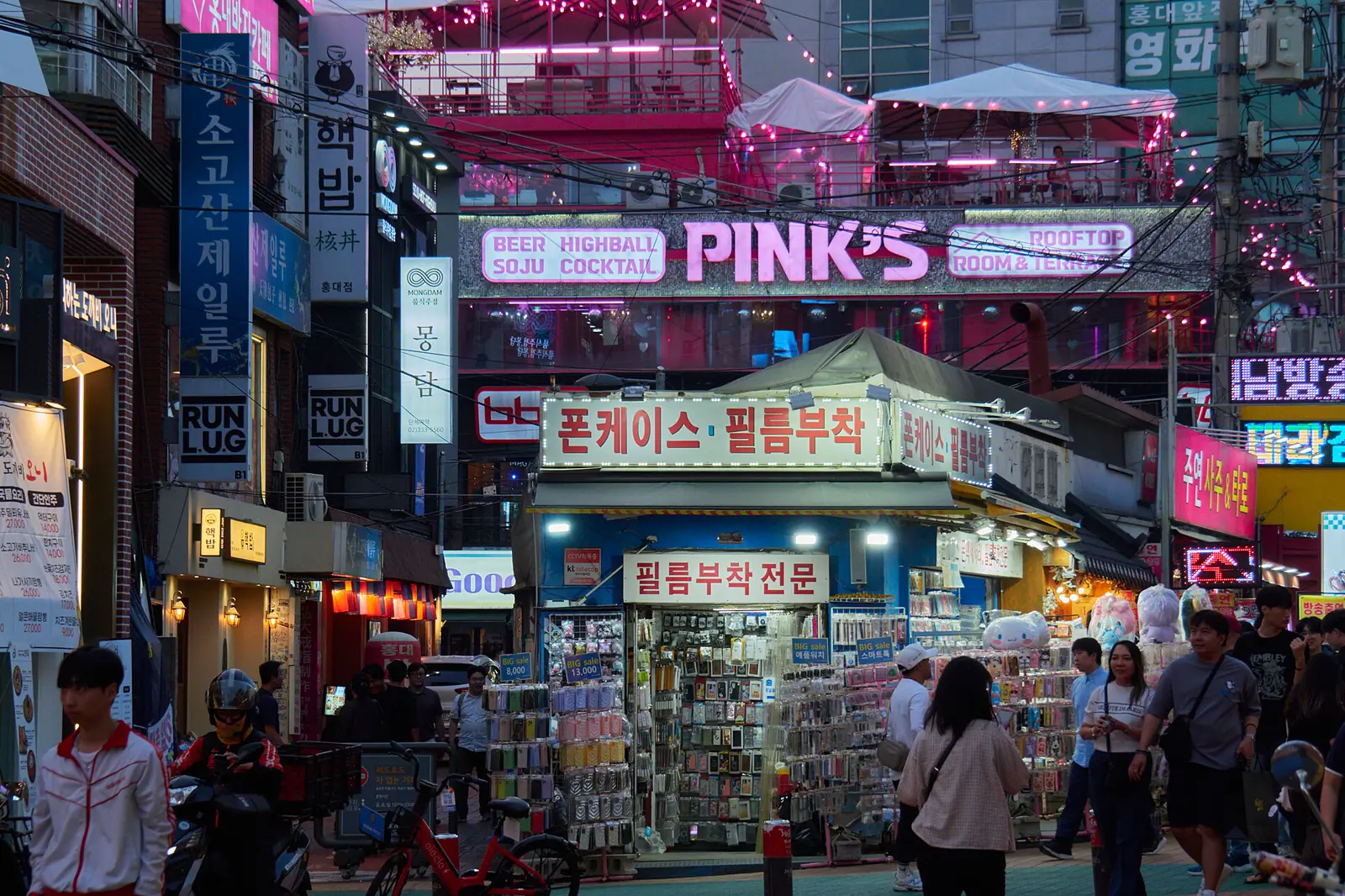 Colorful storefronts and pedestrians around Hongdae at night