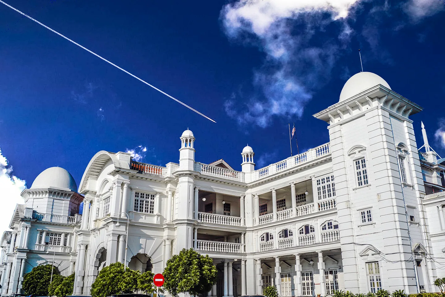 White domes and arcades of Ipoh Railway Station beneath a deep blue sky