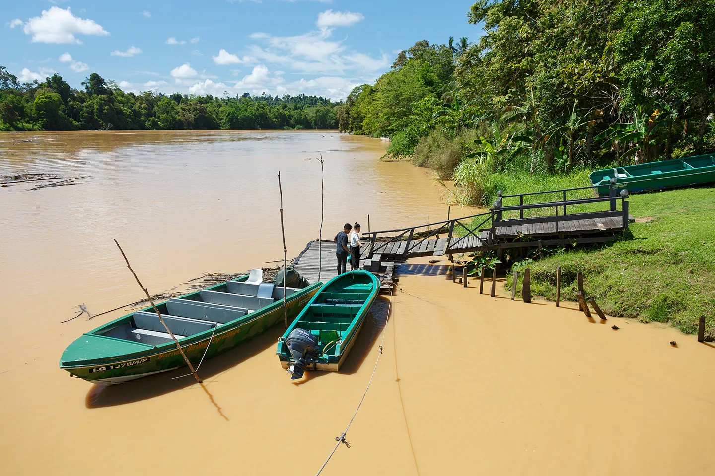 Small river boats tied beside the brown Kinabatangan River at Sukau