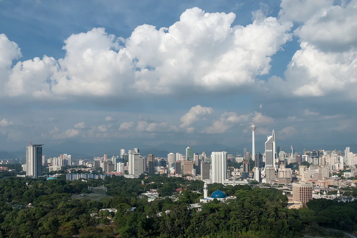 Kuala Lumpur skyline rising beyond a broad green foreground