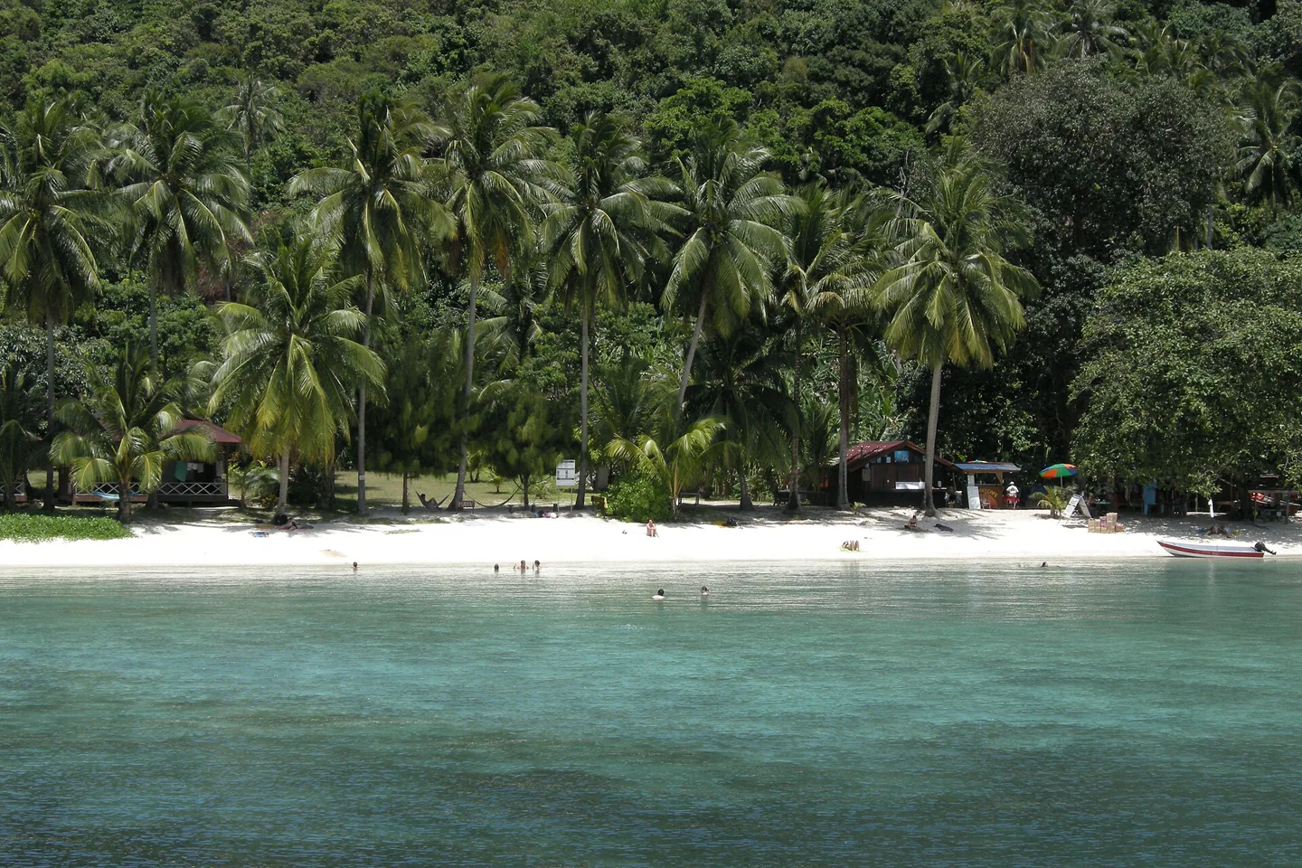 Pale beach, palms and clear water on Perhentian Kecil