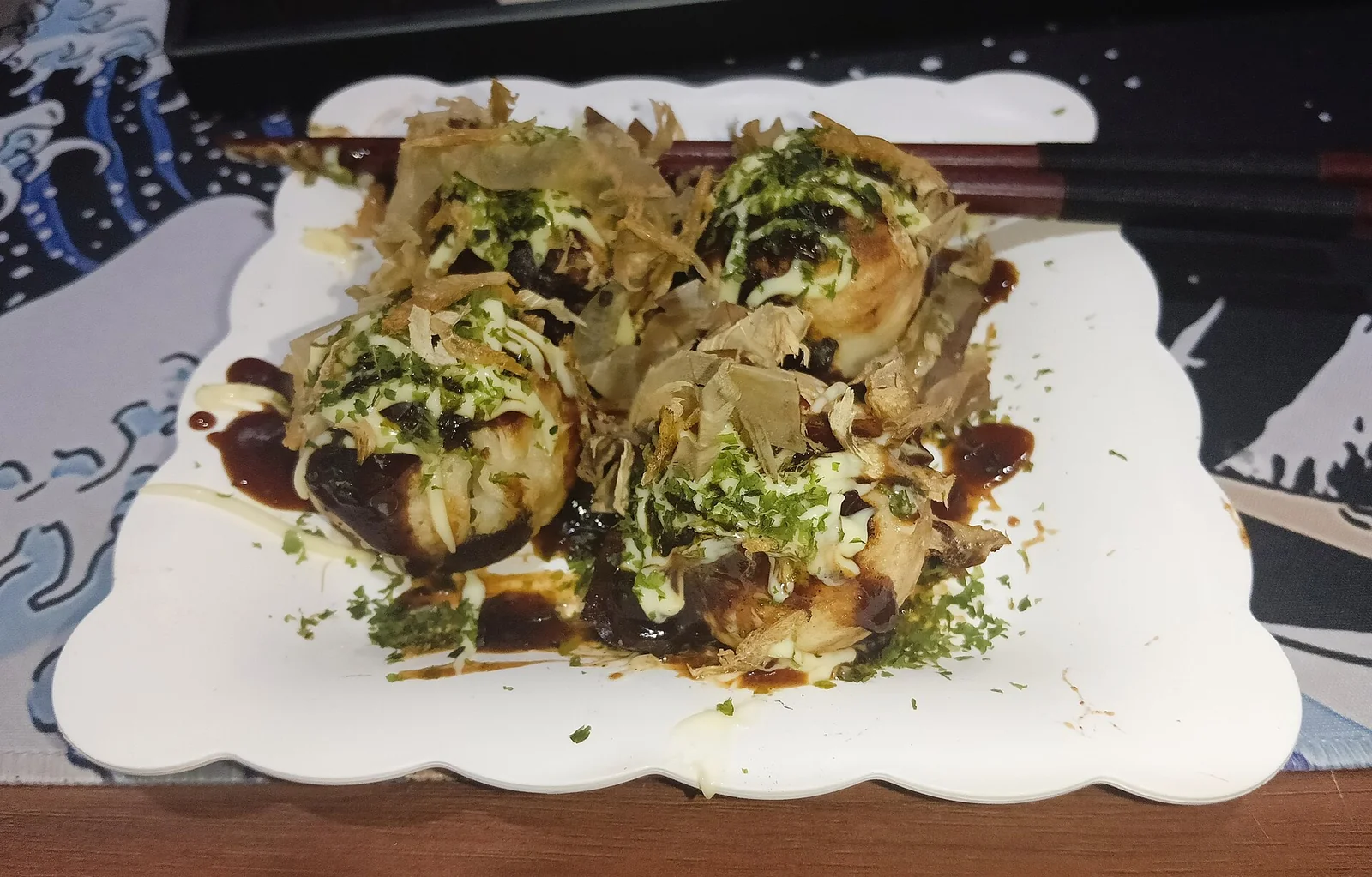 A plate of takoyaki topped with sauce and bonito flakes