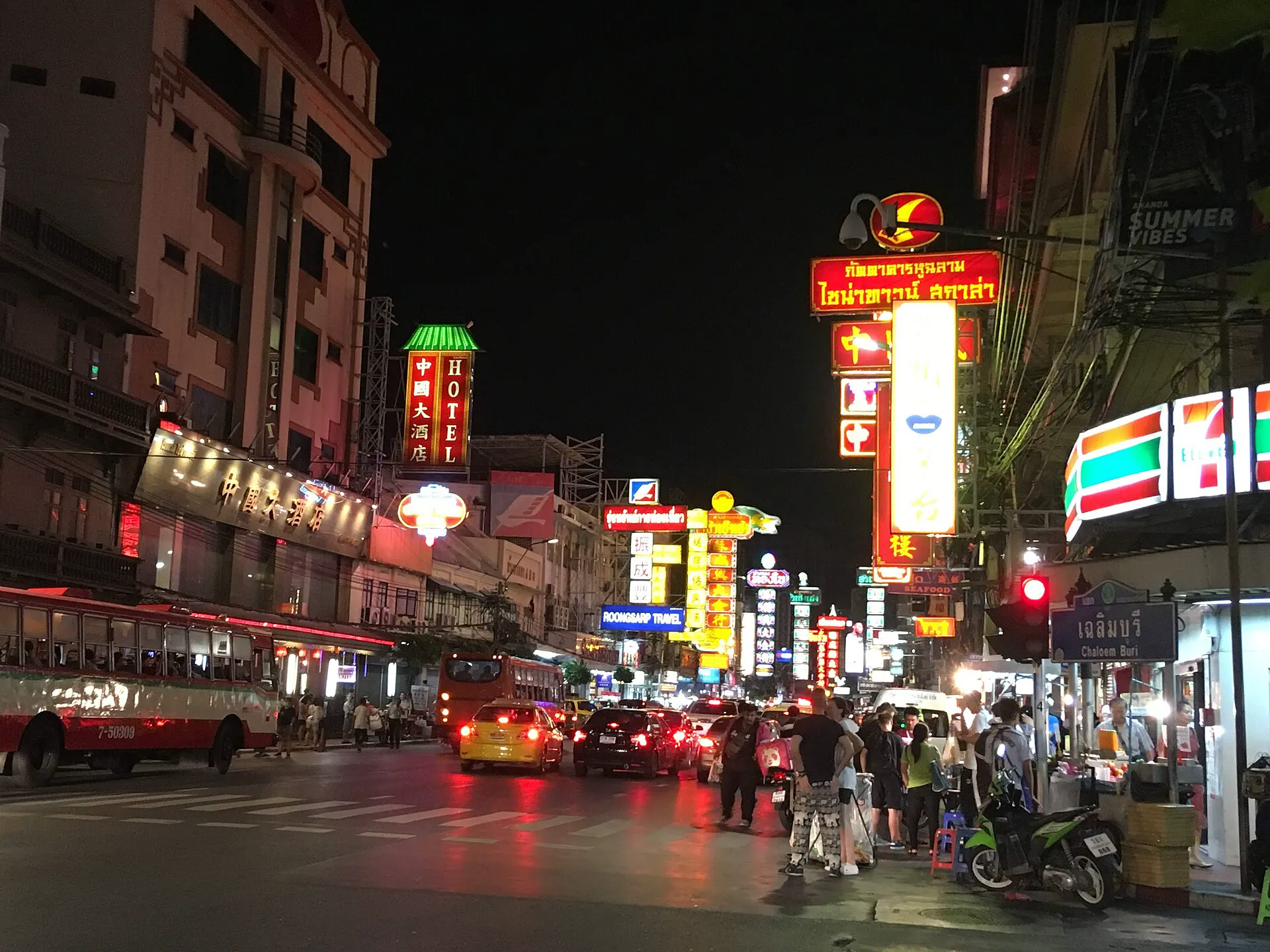 Neon signs, buses and food stalls along Yaowarat Road at night